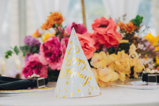 Chapeu de festa com estrelas douradas diante de flores, em paleta clean e sofisticada