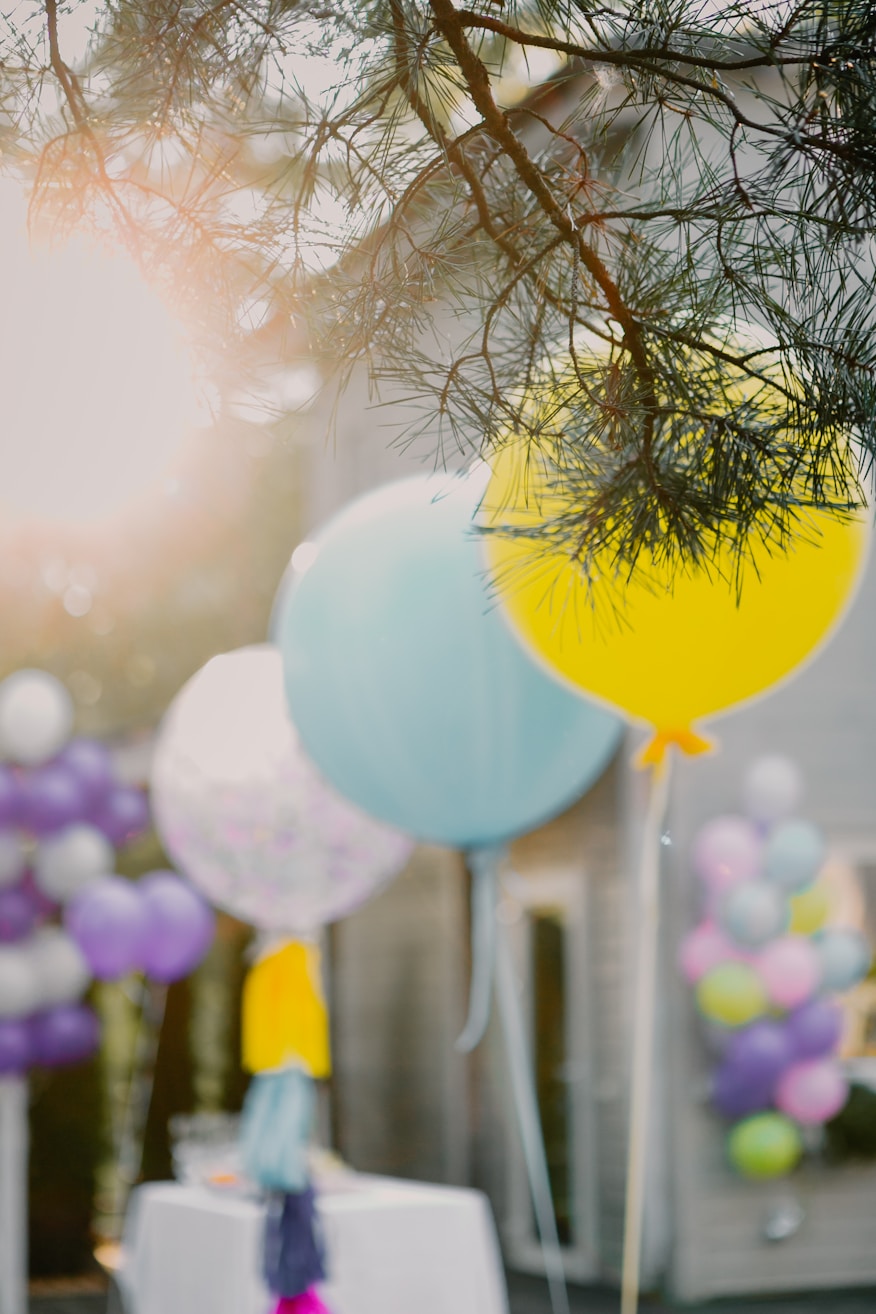 Balões coloridos pendurados em árvore ao ar livre em decoração de festa infantil garden party