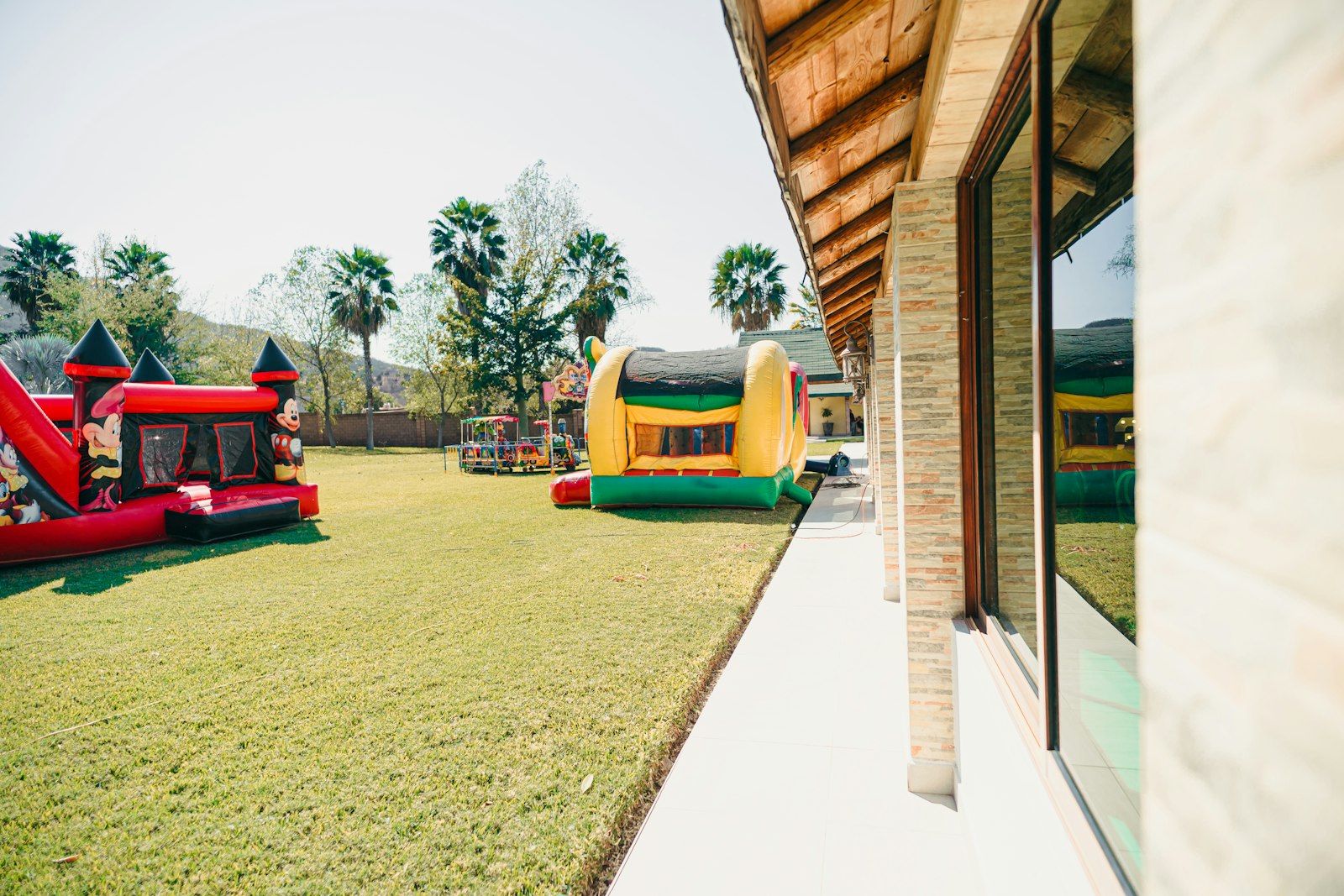 Dois brinquedos infláveis coloridos instalados em gramado de quintal
