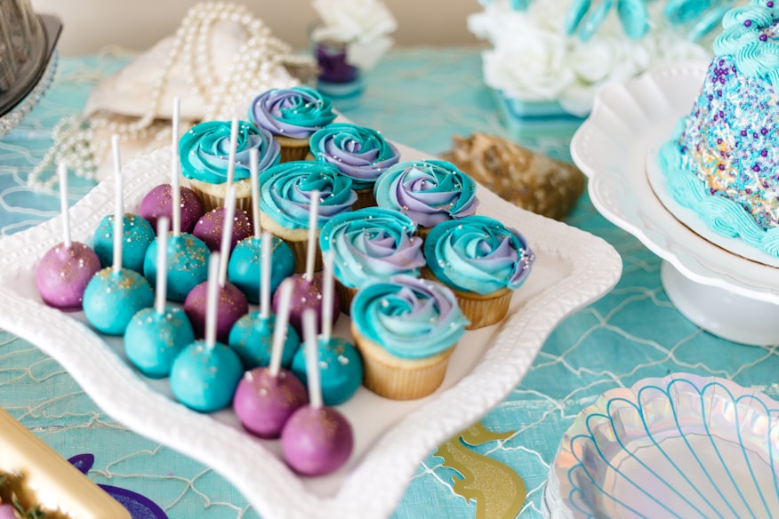 Cake pops brancos e rosas, merengues e cupcakes em mesa de doces