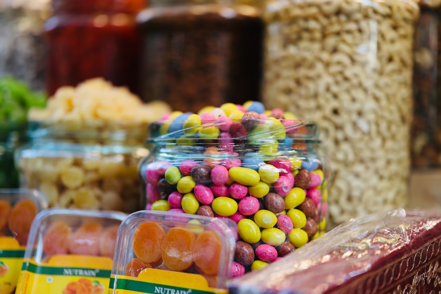 Potes de vidro com balas e doces coloridos em mesa de festa infantil